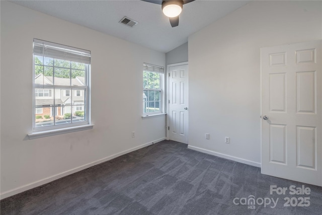 unfurnished room featuring visible vents, dark carpet, baseboards, ceiling fan, and vaulted ceiling