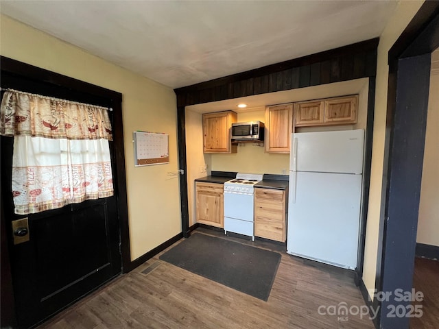 kitchen with light brown cabinets, dark hardwood / wood-style floors, and white appliances