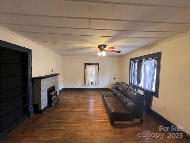 living room with ceiling fan, ornamental molding, a fireplace, and dark hardwood / wood-style floors