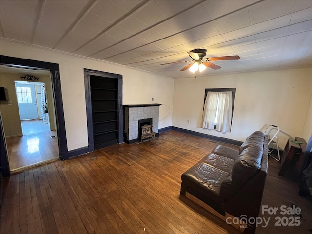 unfurnished living room featuring ceiling fan, wood-type flooring, a fireplace, and ornamental molding