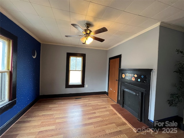 unfurnished living room featuring ceiling fan, light wood-type flooring, and ornamental molding