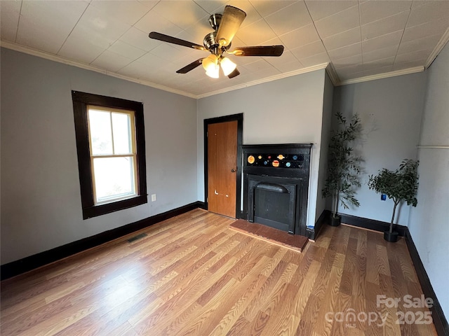 unfurnished living room with ceiling fan, a fireplace, crown molding, and light hardwood / wood-style floors