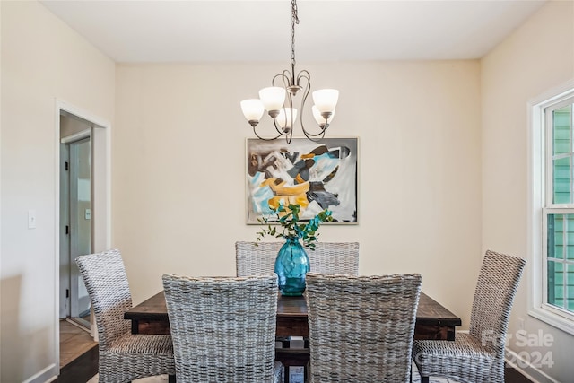 dining space with wood-type flooring and an inviting chandelier