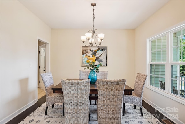 dining area with dark wood-type flooring and a notable chandelier