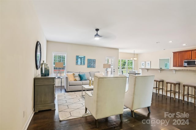 living room with dark hardwood / wood-style floors and ceiling fan with notable chandelier