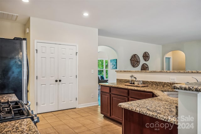 kitchen featuring light tile patterned flooring, stainless steel appliances, and light stone countertops