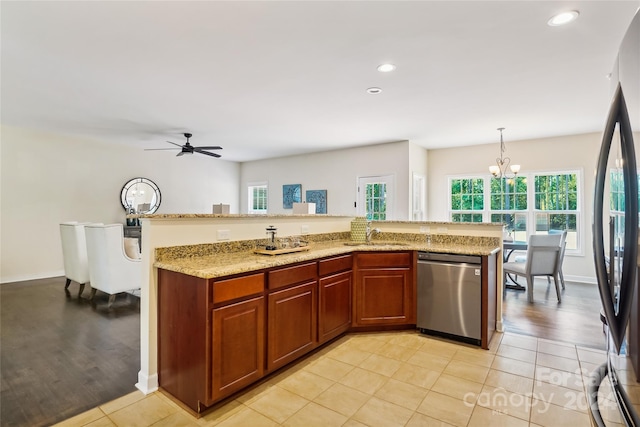 kitchen with ceiling fan with notable chandelier, light hardwood / wood-style flooring, dishwasher, light stone countertops, and hanging light fixtures