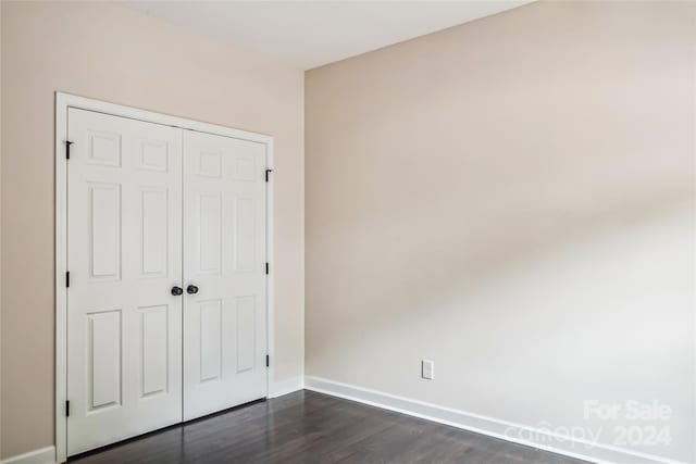 unfurnished bedroom with dark hardwood / wood-style floors and a closet