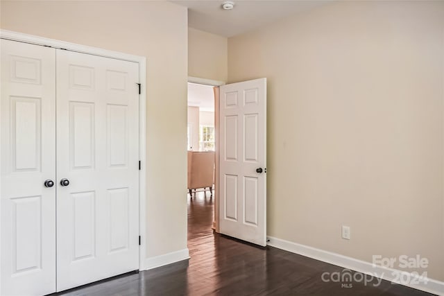 unfurnished bedroom with dark hardwood / wood-style flooring and a closet