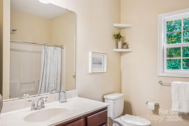 bathroom with a shower with curtain, vanity, toilet, and a healthy amount of sunlight