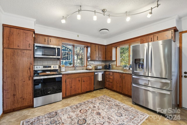 kitchen featuring stainless steel appliances, a healthy amount of sunlight, and a textured ceiling