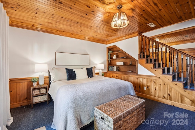 bedroom with dark colored carpet, wood ceiling, wooden walls, a chandelier, and crown molding