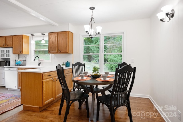 dining area with light wood-type flooring, a notable chandelier, and sink