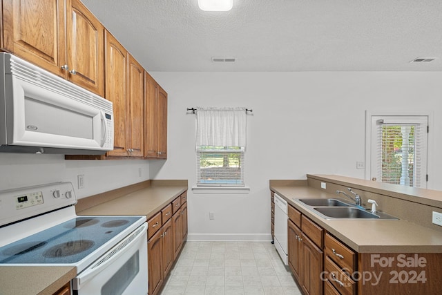 kitchen featuring white appliances, a textured ceiling, and sink