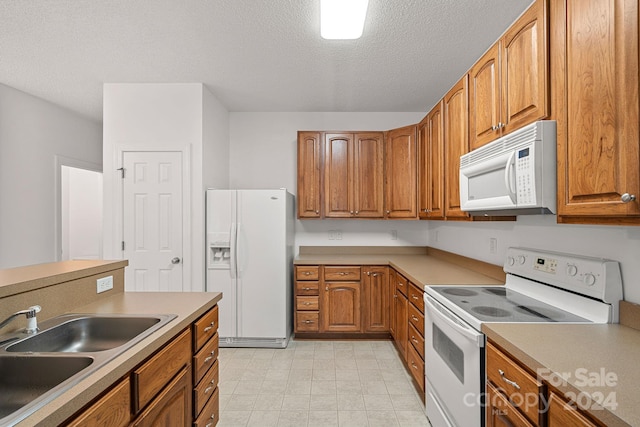 kitchen featuring white appliances, sink, and a textured ceiling