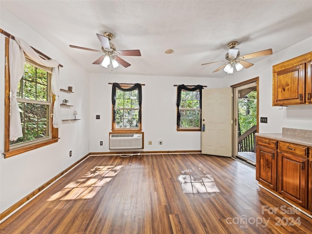 interior space featuring ceiling fan, a textured ceiling, dark hardwood / wood-style flooring, and a wall unit AC