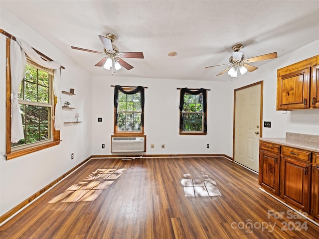 interior space featuring a textured ceiling, dark hardwood / wood-style floors, ceiling fan, and a wall mounted air conditioner