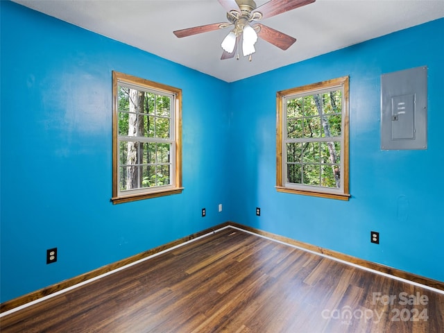 empty room featuring hardwood / wood-style floors, ceiling fan, electric panel, and a healthy amount of sunlight