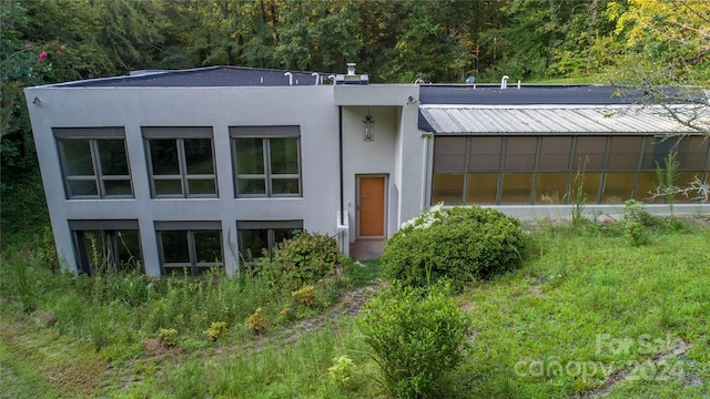 view of front of house featuring a wooded view and stucco siding