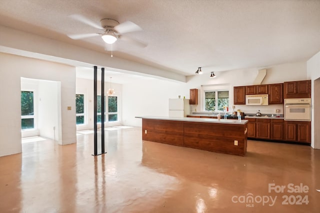 kitchen featuring ceiling fan with notable chandelier, a textured ceiling, a kitchen island, pendant lighting, and white appliances