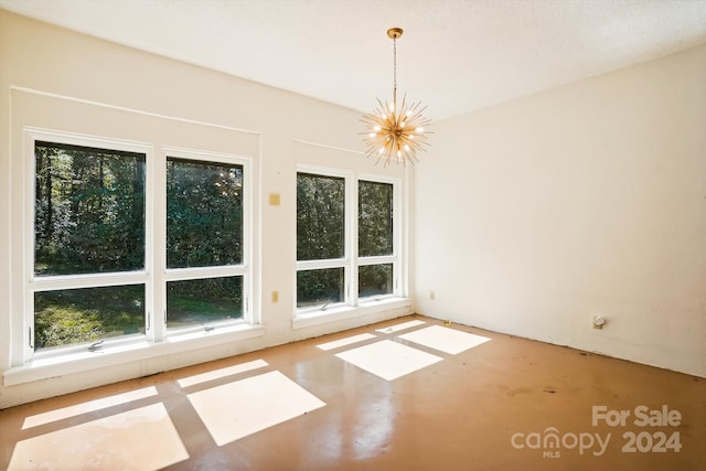 interior space featuring concrete floors, plenty of natural light, and a notable chandelier