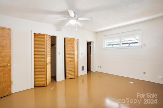 unfurnished bedroom featuring a textured ceiling, multiple closets, and ceiling fan