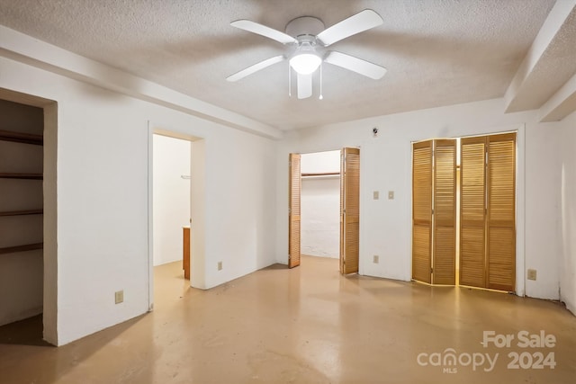 unfurnished bedroom featuring ceiling fan, a textured ceiling, and multiple closets