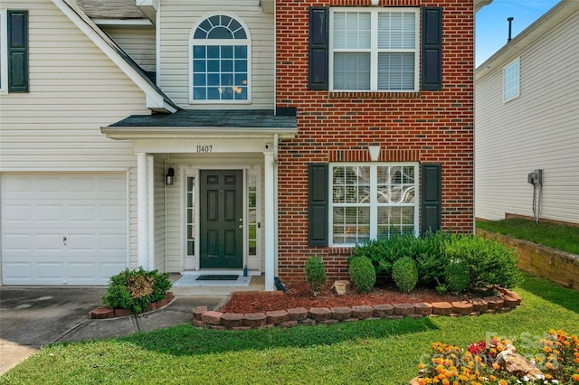 doorway to property with driveway and brick siding