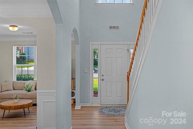 entrance foyer featuring visible vents, arched walkways, wood finished floors, and ornamental molding