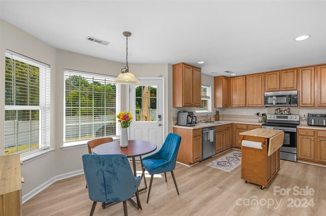 kitchen with light countertops, visible vents, light wood-style flooring, appliances with stainless steel finishes, and a sink