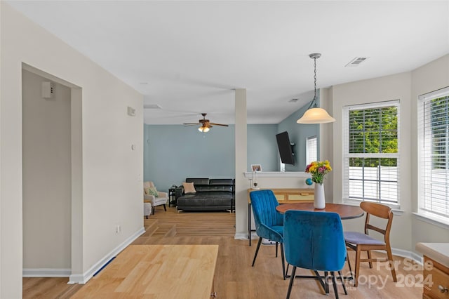 dining space with a ceiling fan, wood finished floors, visible vents, and baseboards