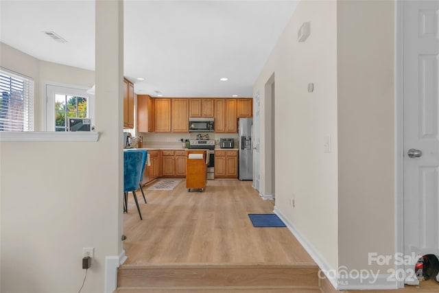 kitchen with stainless steel appliances, light countertops, visible vents, light wood-style floors, and baseboards