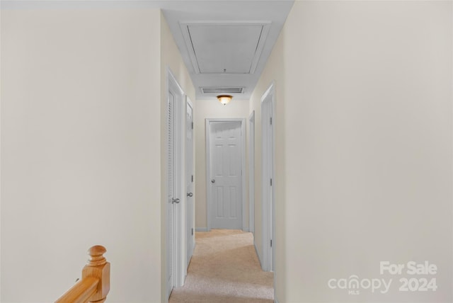 hall featuring attic access, visible vents, and light colored carpet