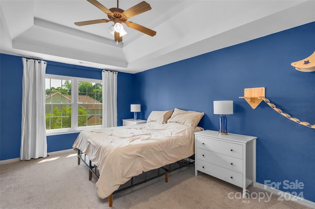 bedroom featuring ceiling fan, carpet flooring, a raised ceiling, and baseboards