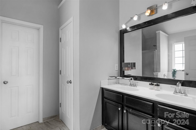 full bathroom featuring double vanity, marble finish floor, an enclosed shower, and a sink