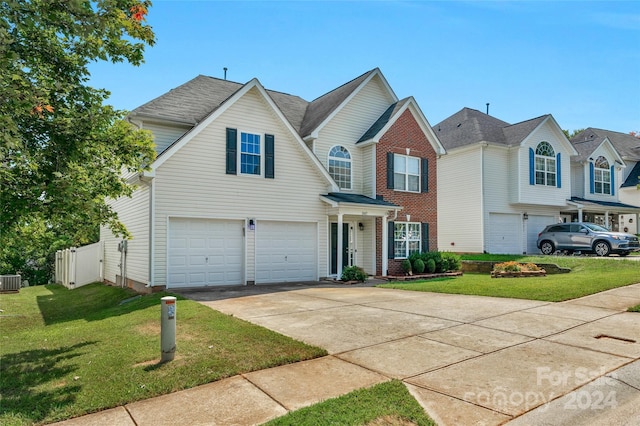 traditional home featuring a garage, driveway, fence, cooling unit, and a front yard