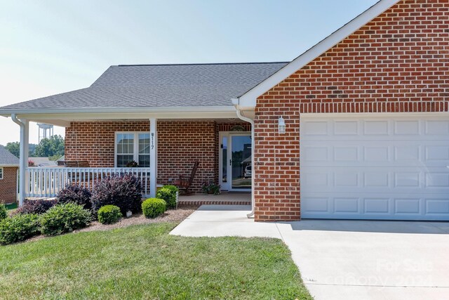 view of front of house featuring a garage, a front lawn, and covered porch