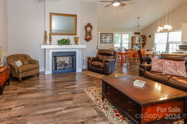 living room with ceiling fan with notable chandelier, high vaulted ceiling, and hardwood / wood-style flooring