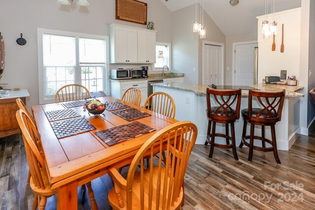 dining area with an inviting chandelier, high vaulted ceiling, and dark hardwood / wood-style flooring