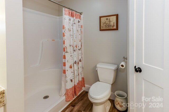 bathroom with walk in shower, toilet, and wood-type flooring