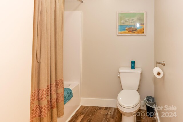 bathroom featuring shower / bath combo with shower curtain, toilet, and wood-type flooring