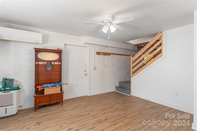 interior space with a wall mounted AC, ceiling fan, and light wood-type flooring