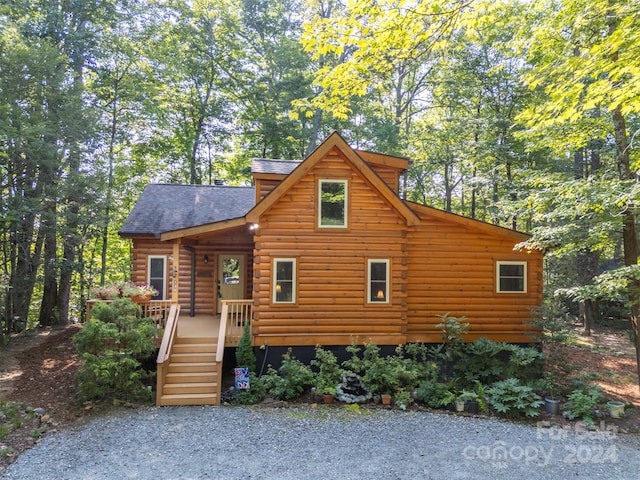 log cabin with log exterior, a wooden deck, and roof with shingles