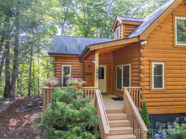 exterior space featuring log siding and a shingled roof