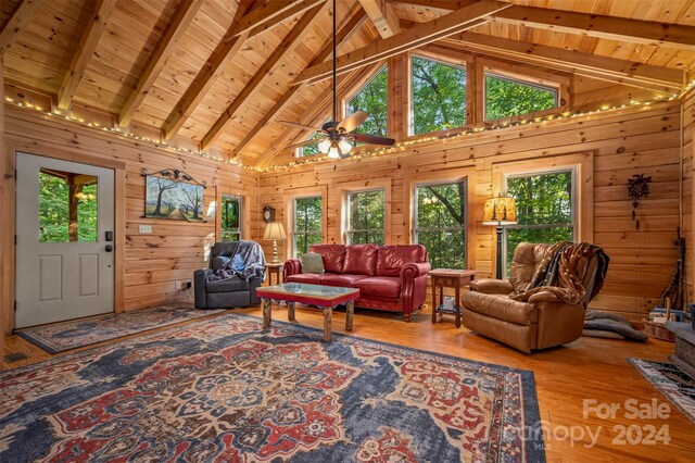 living room with wood ceiling, high vaulted ceiling, and wood walls