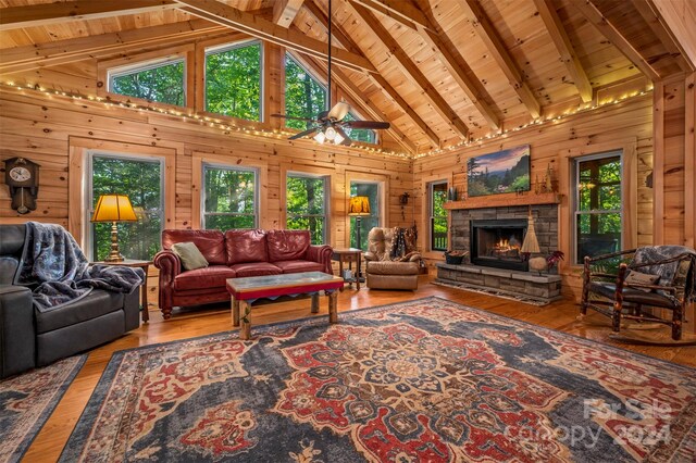 living room with high vaulted ceiling, wood walls, a stone fireplace, wooden ceiling, and hardwood / wood-style flooring