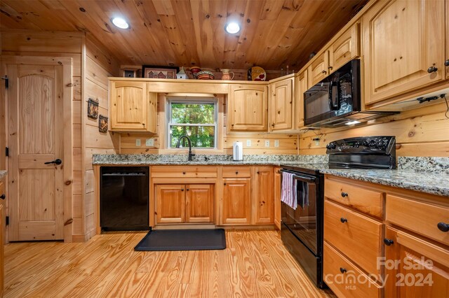 kitchen featuring wooden walls, light wood-type flooring, wood ceiling, light stone counters, and black appliances