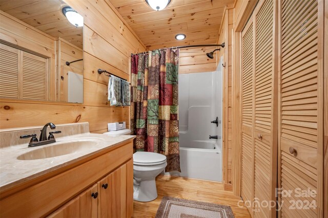 full bathroom featuring toilet, hardwood / wood-style floors, wooden walls, vanity, and wooden ceiling