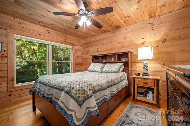 bedroom featuring ceiling fan, hardwood / wood-style floors, wooden walls, and wooden ceiling