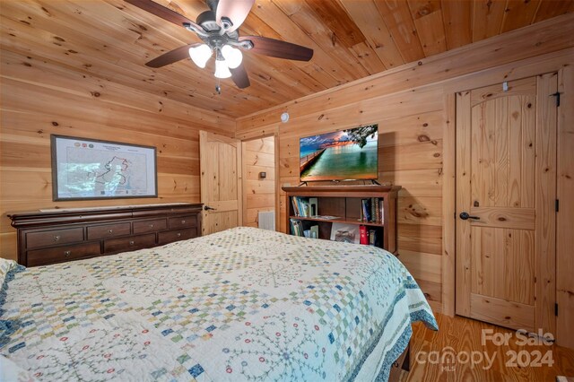 bedroom with hardwood / wood-style floors, ceiling fan, wood walls, and wooden ceiling